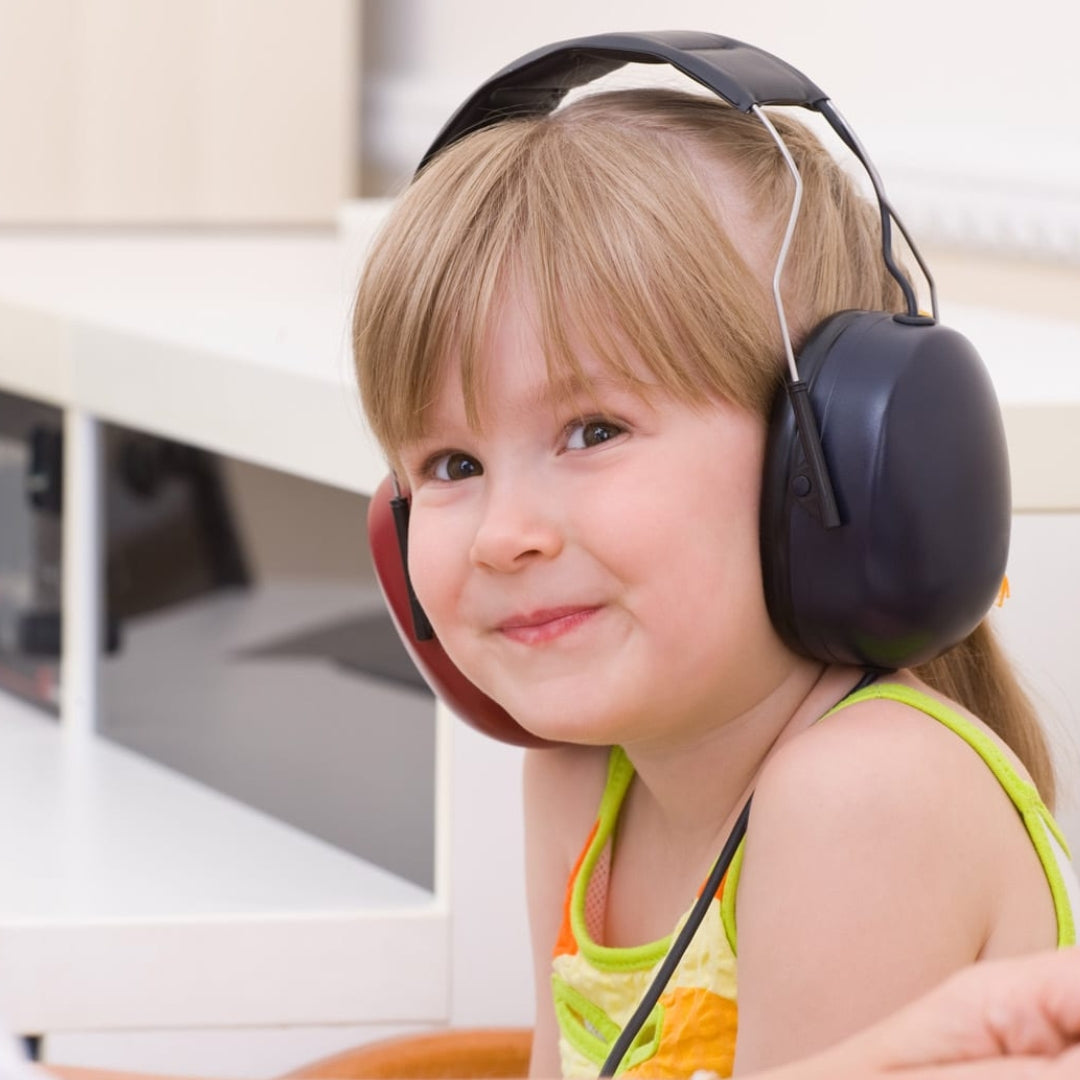 A young girl in a classroom setting wears a pair of headphones