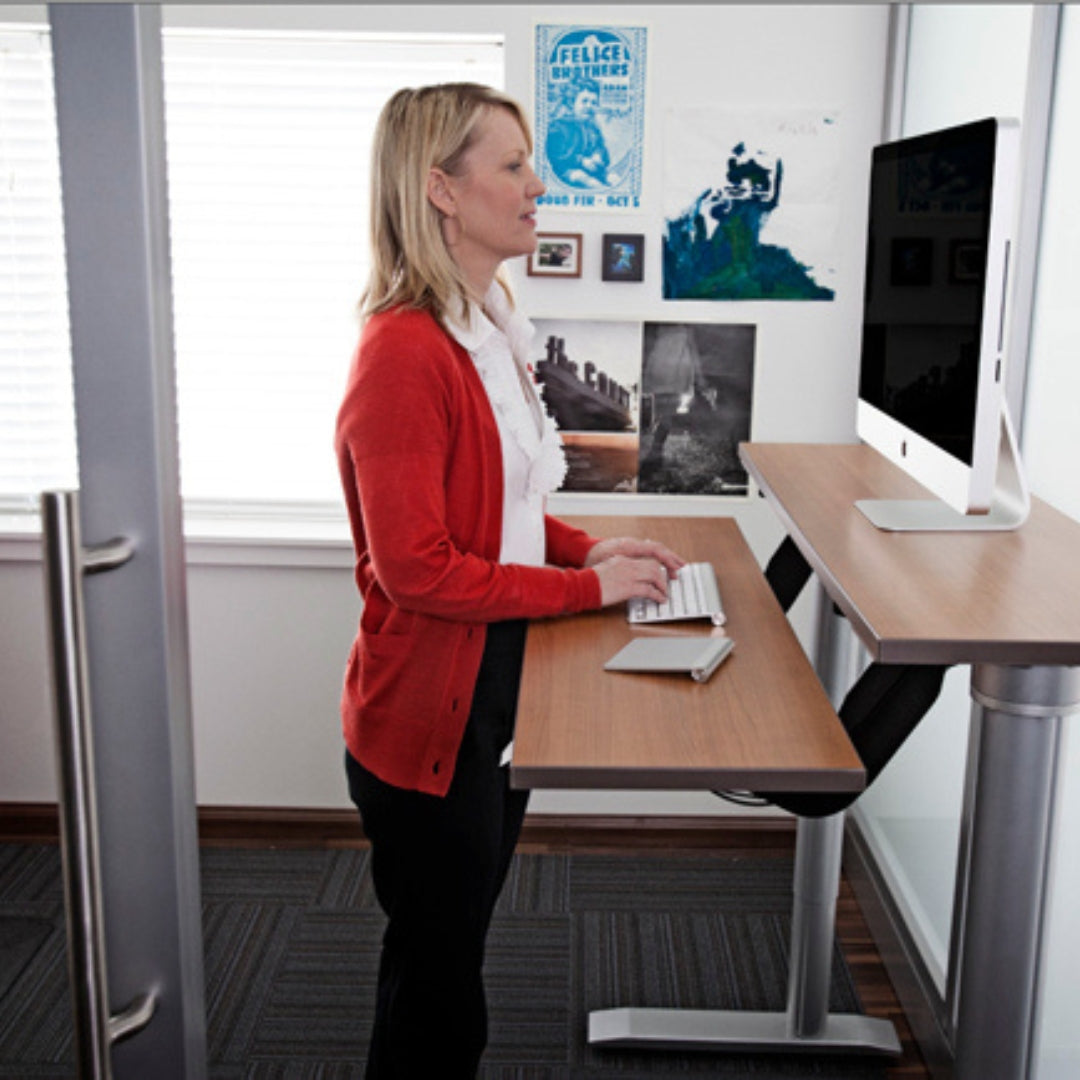 A woman stands at an accessible workstation in an office environment