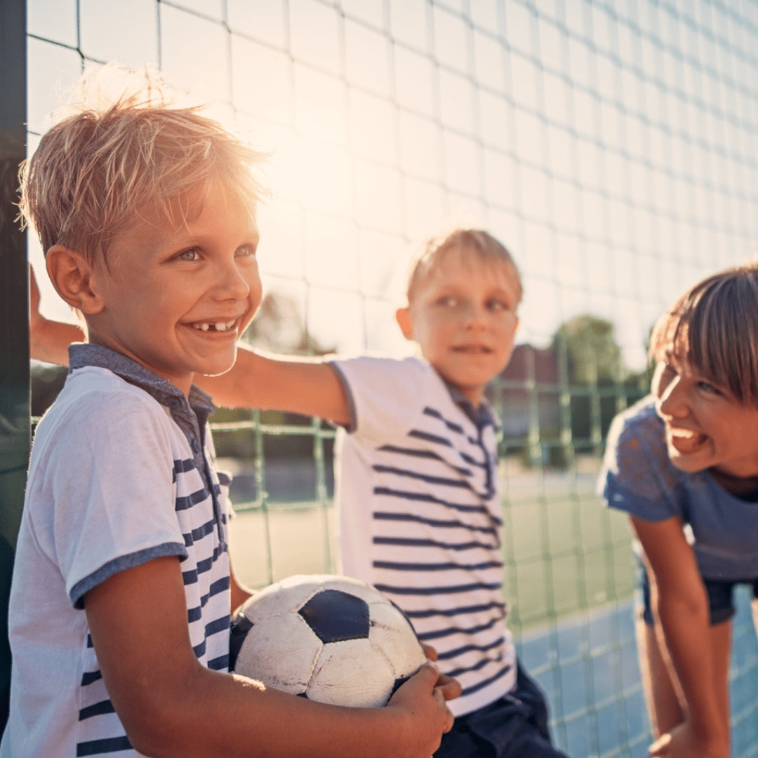 Three boys smile as they play soccer