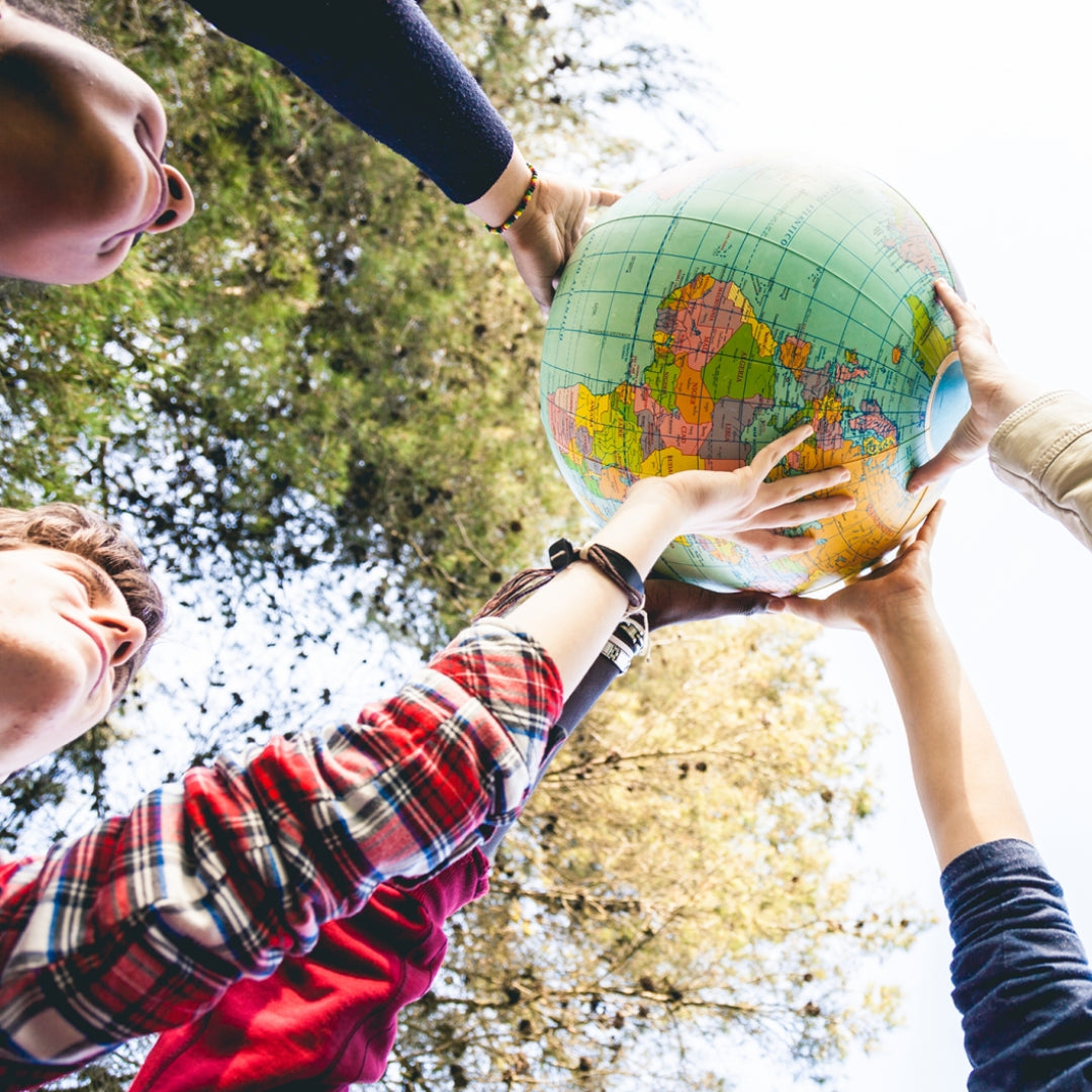 A group of children hold up a globe