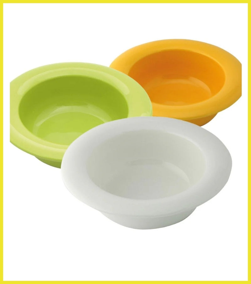 Three colorful silicone bowls in green, orange, and white on a white background