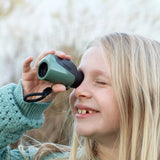Child using a green monocular with a blurred natural background