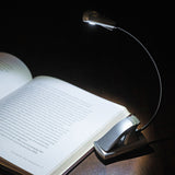 Reading lamp with flexible neck illuminating an open book on a dark background