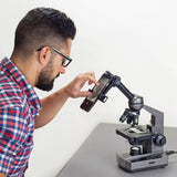 Man using a smartphone with a microscope attachment on a white background