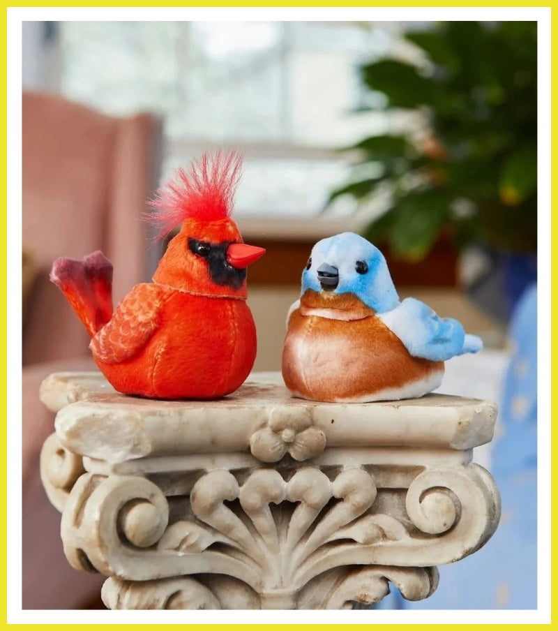 Two decorative birds, one red and one blue, on a stone pedestal with a blurred background.
