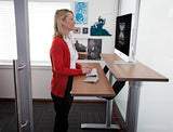 Woman standing and working on a computer on the Vox Adjustable Dual Surface Workstation