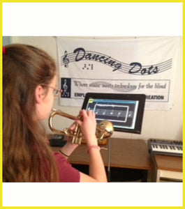 Girl playing trumpet while reading large print music score on a monitor